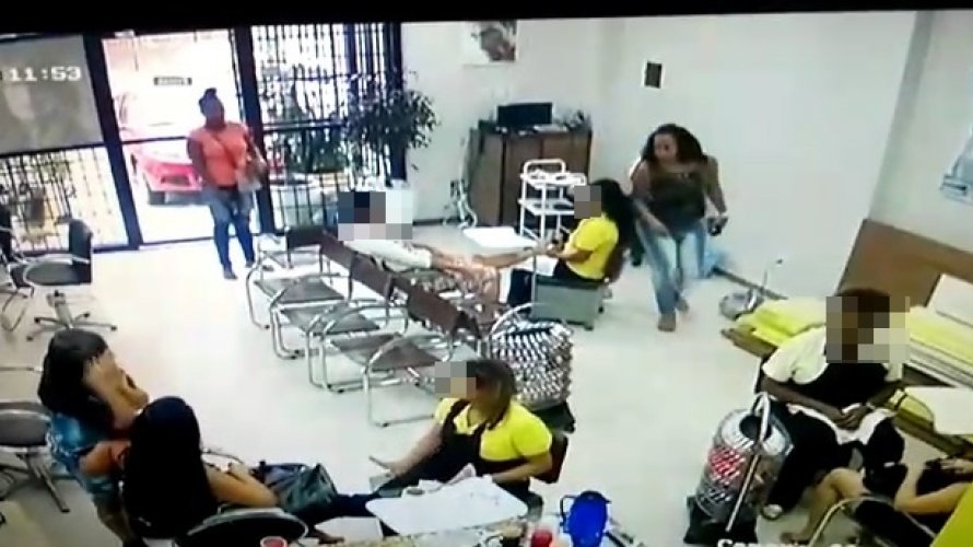 Enquanto uma delas saca a arma da bolsa, a outra mulher recolhe aparelhos celulares de clientes e funcionárias.