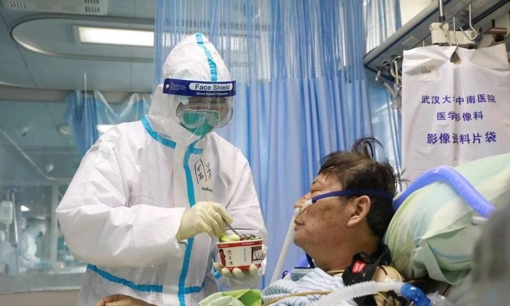 Os reinos se abalam, os governos caem, os homens entram em desespero, mas o Todo Poderoso permanece inabalável. Enfermeira alimenta paciente com coronavirus. (Foto: China Daily)