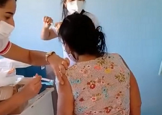 Técnica de enfermagem fura o braço da idosa com a agulha mas não pressiona a ampola para injetar o líquido imunizante (Foto: Reprodução)