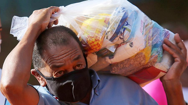 Homem carrega cesta básica distribuída pelo G10 das Favelas