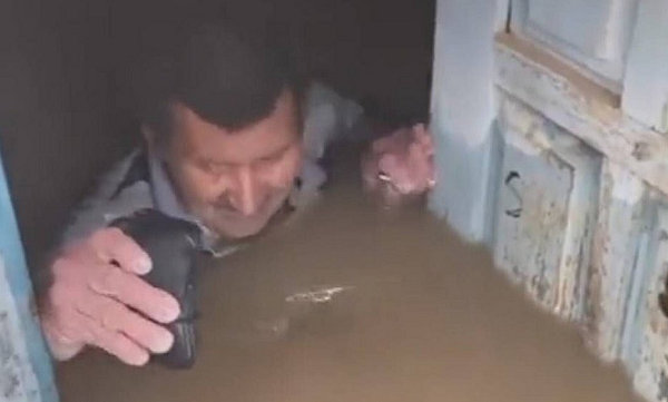 Nas imagens é possível ver que ele tem dificuldade para abrir a porta da casa completamente inundada e só consegue retirar uma carteira (Foto: Reprodução)