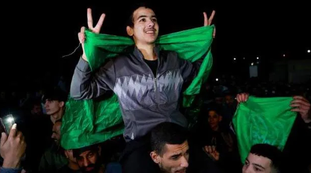 Um dos palestinos libertados é carregado nos ombros de um homem, envolto em uma bandeira (Foto: Reuters)